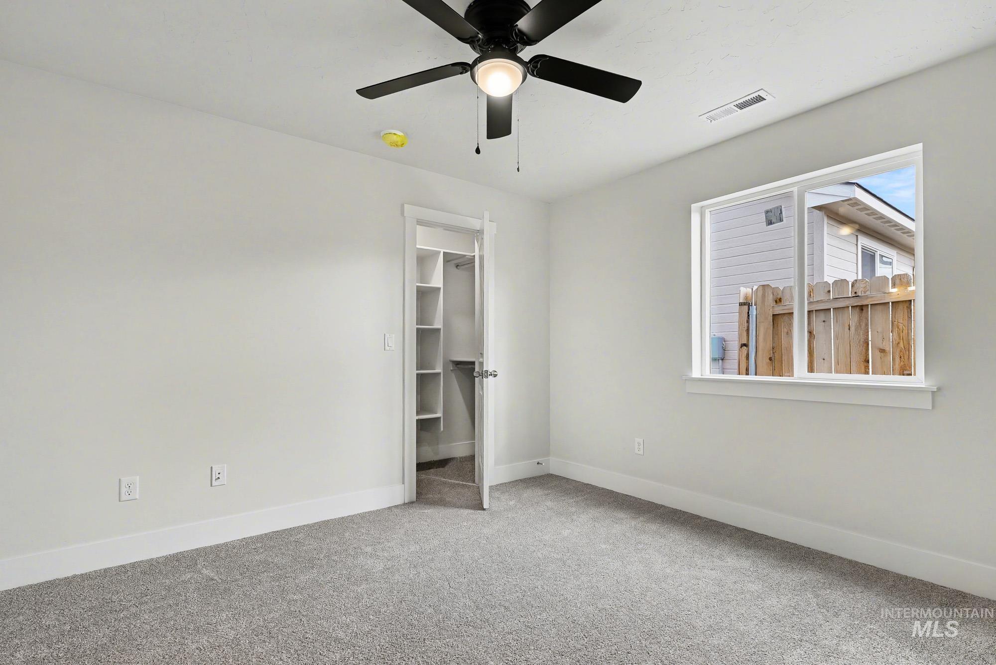 326 Packer Lane Homedale, ID 83628 - Photo 14 of 24 Unfurnished bedroom with a walk in closet, light carpet, and ceiling fan