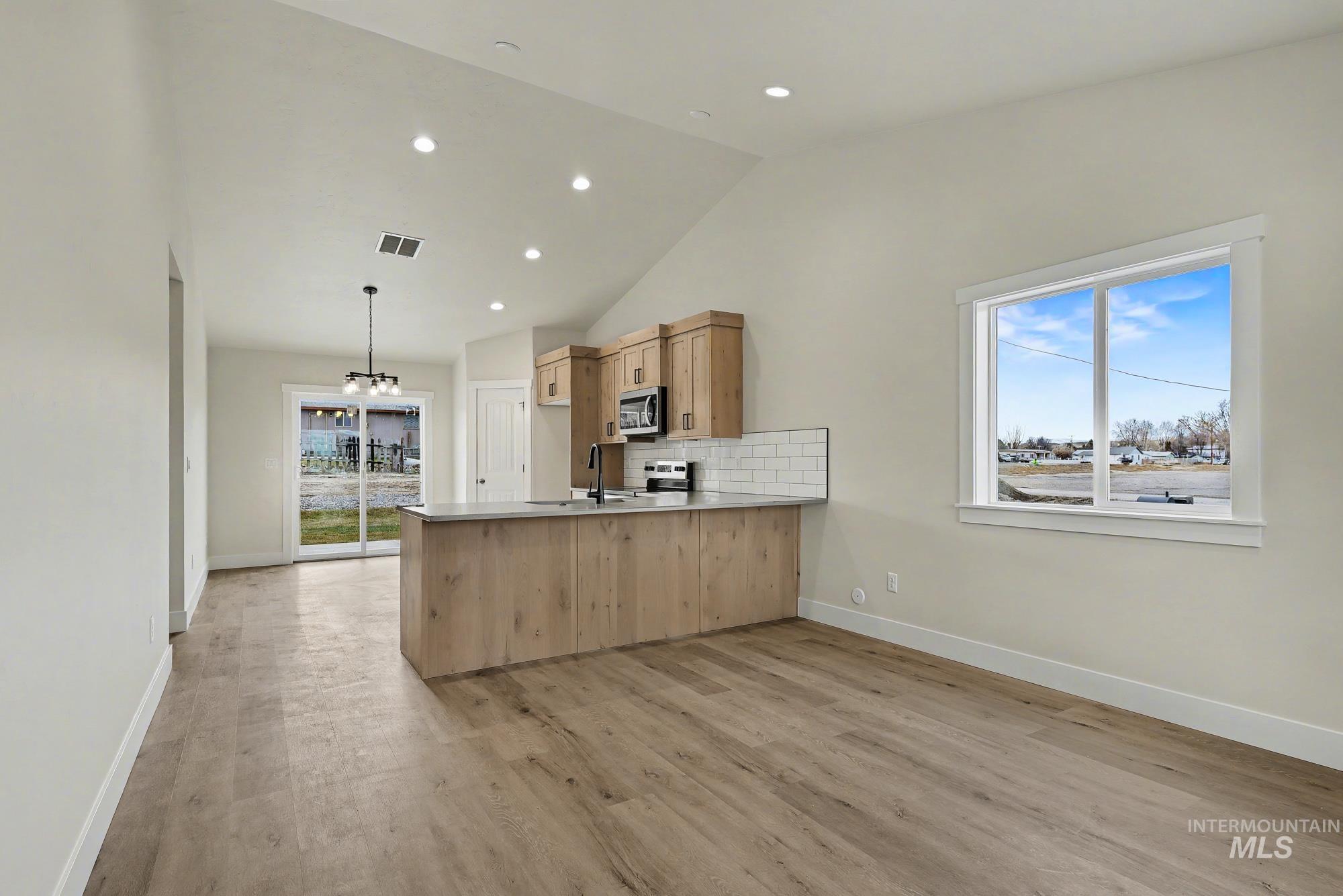 326 Packer Lane Homedale, ID 83628 - Photo 2 of 24 Kitchen with tasteful backsplash, pendant lighting, light wood-type flooring, lofted ceiling, and light countertops