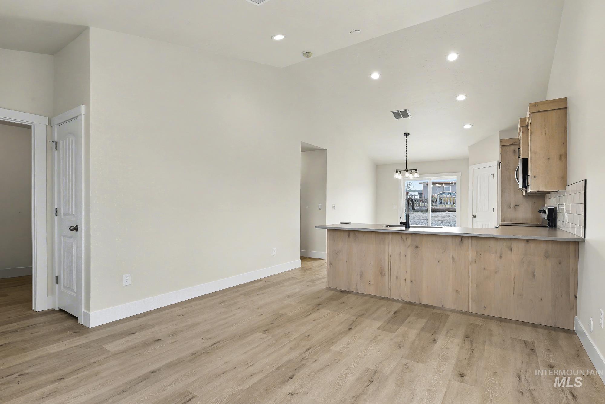 326 Packer Lane Homedale, ID 83628 - Photo 4 of 24 Kitchen with hanging light fixtures, a peninsula, light brown cabinetry, recessed lighting, and lofted ceiling