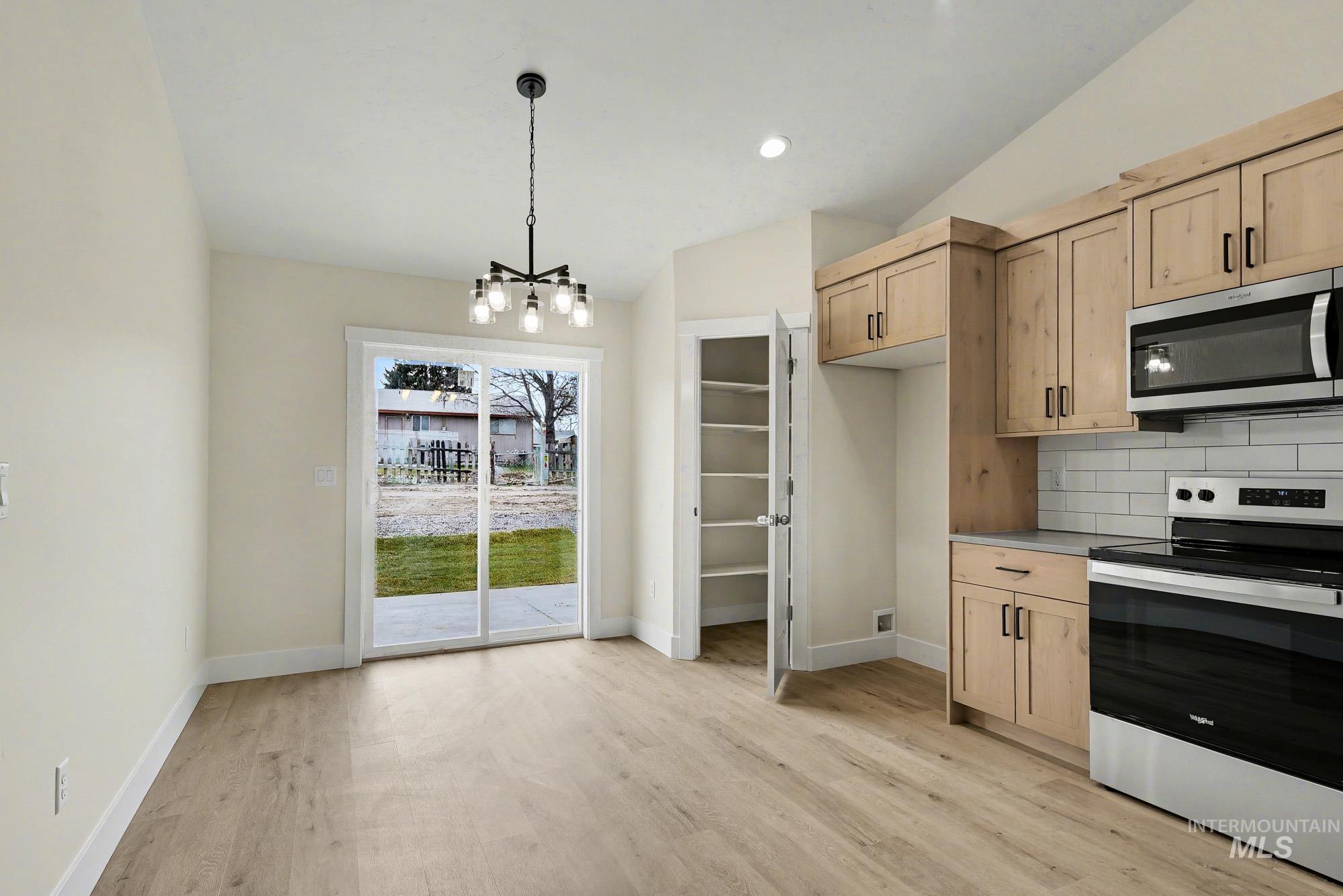 326 Packer Lane Homedale, ID 83628 - Photo 8 of 24 Kitchen featuring appliances with stainless steel finishes, light brown cabinetry, backsplash, vaulted ceiling, and pendant lighting