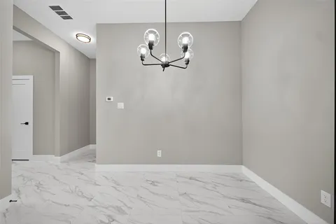 a view of a room with a hanging light and kitchen view