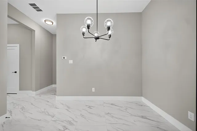 a view of a room with a hanging light and kitchen view