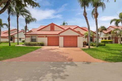 front view of a house with a yard and palm trees