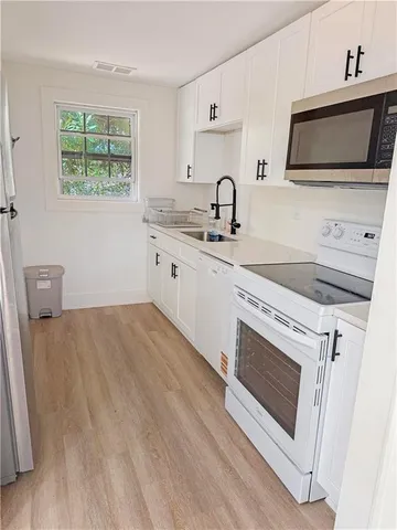 a kitchen with stainless steel appliances white cabinets a stove a sink and a microwave