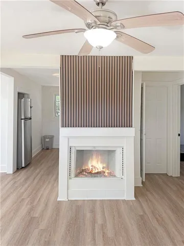 a view of an empty room with wooden floor fireplace and a window