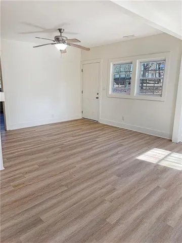 a view of an empty room with wooden floor and a window