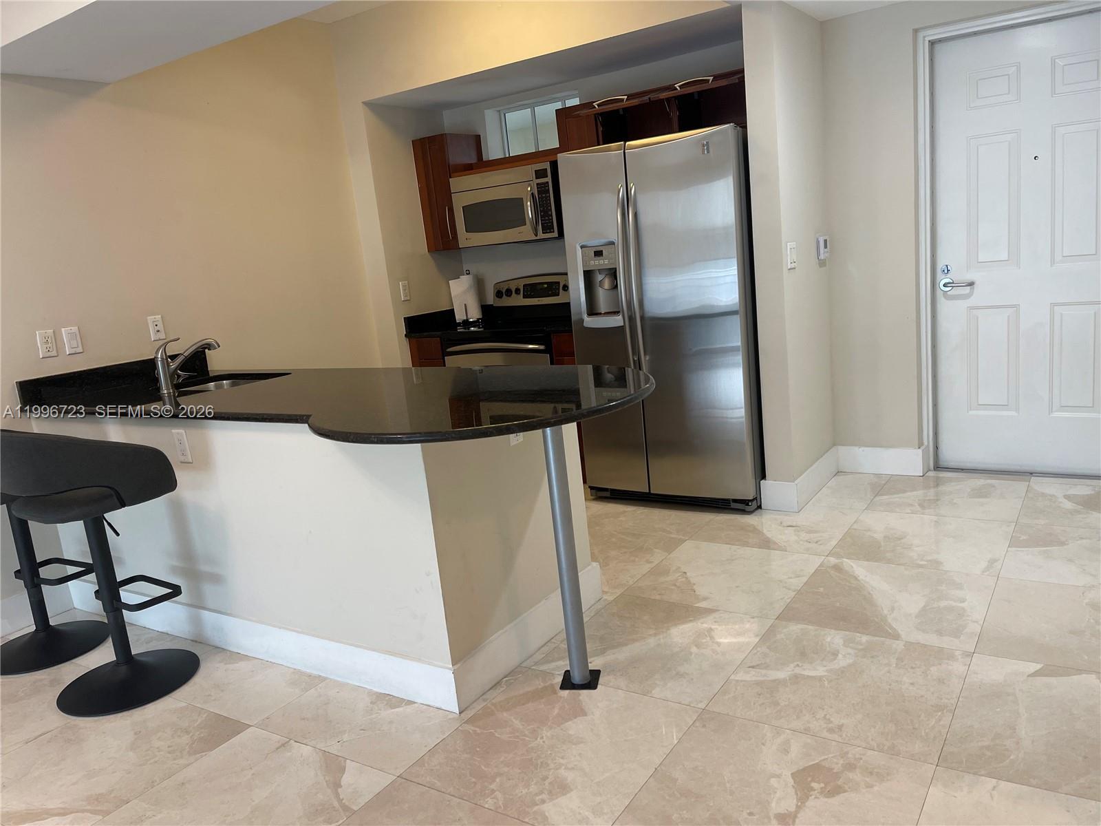 7290 Southwest 90th Street, Unit 307 Miami, FL 33156 - Photo 3 of 14 a kitchen with a refrigerator and a counter top space