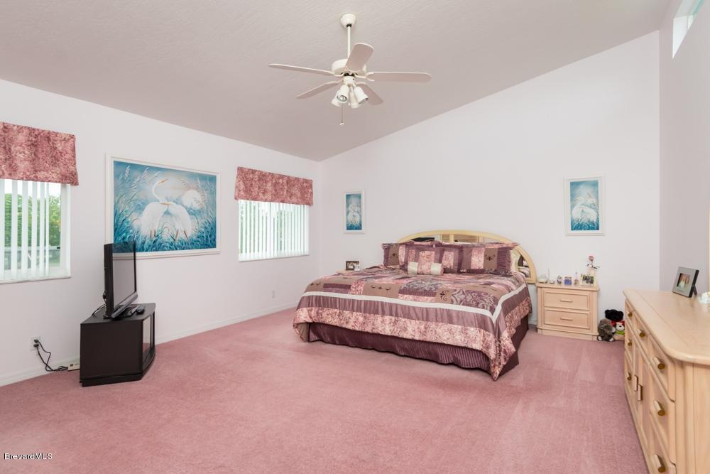 3570 Big Pine Road Melbourne, FL 32934 - Photo 14 of 27 a spacious bedroom with a bed and a chandelier