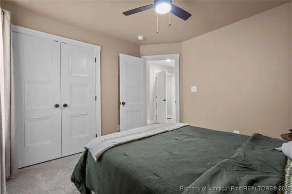 a bedroom with a large bed and a chandelier fan