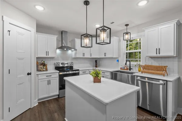 a kitchen with stainless steel appliances granite countertop a sink a stove a refrigerator and white cabinets with wooden floor