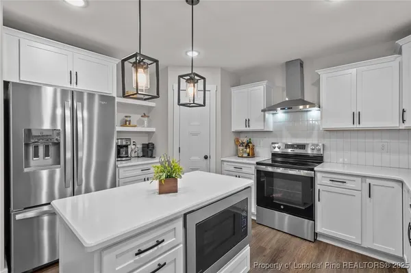 a kitchen with stainless steel appliances granite countertop a sink a stove a refrigerator and a refrigerator with white cabinets