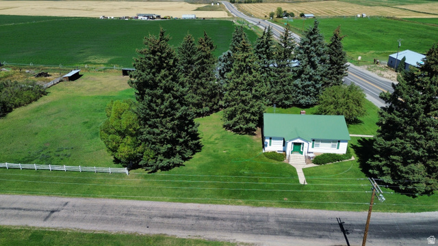 114 West 7th Street Georgetown, ID 83239 - Photo 1 of 71 White siding exterior with a green metal roof, front entryway with steps, surrounding mature trees, and a manicured lawn