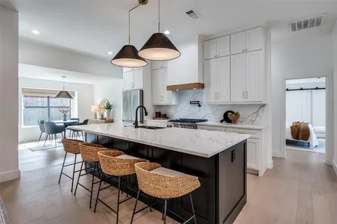 a kitchen with a dining table chairs sink and white cabinets