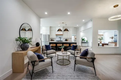 a living room with furniture a potted plant and kitchen view