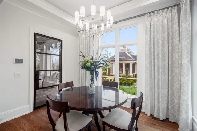 a living room with furniture a chandelier and a dining table with wooden floor