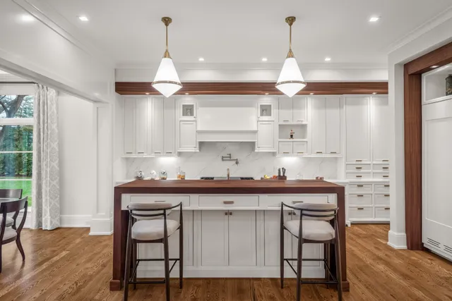 a kitchen with stainless steel appliances granite countertop a dining table chairs sink and cabinets