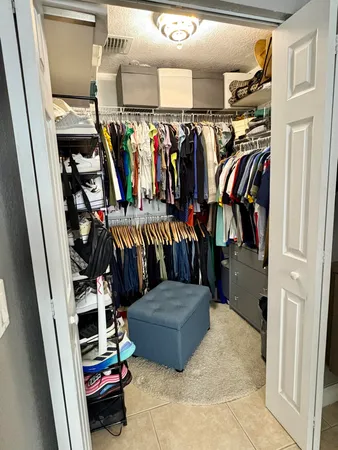 a view of walk in closet with clothes and shoes