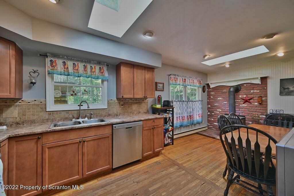 217 Hemlock Road Lake Ariel, PA 18436 - Photo 21 of 54 a kitchen with stainless steel appliances granite countertop a stove a sink dishwasher a dining table and chair with wooden floor