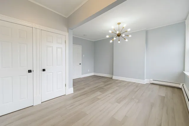 a view of an empty room with chandelier fan and wooden floor