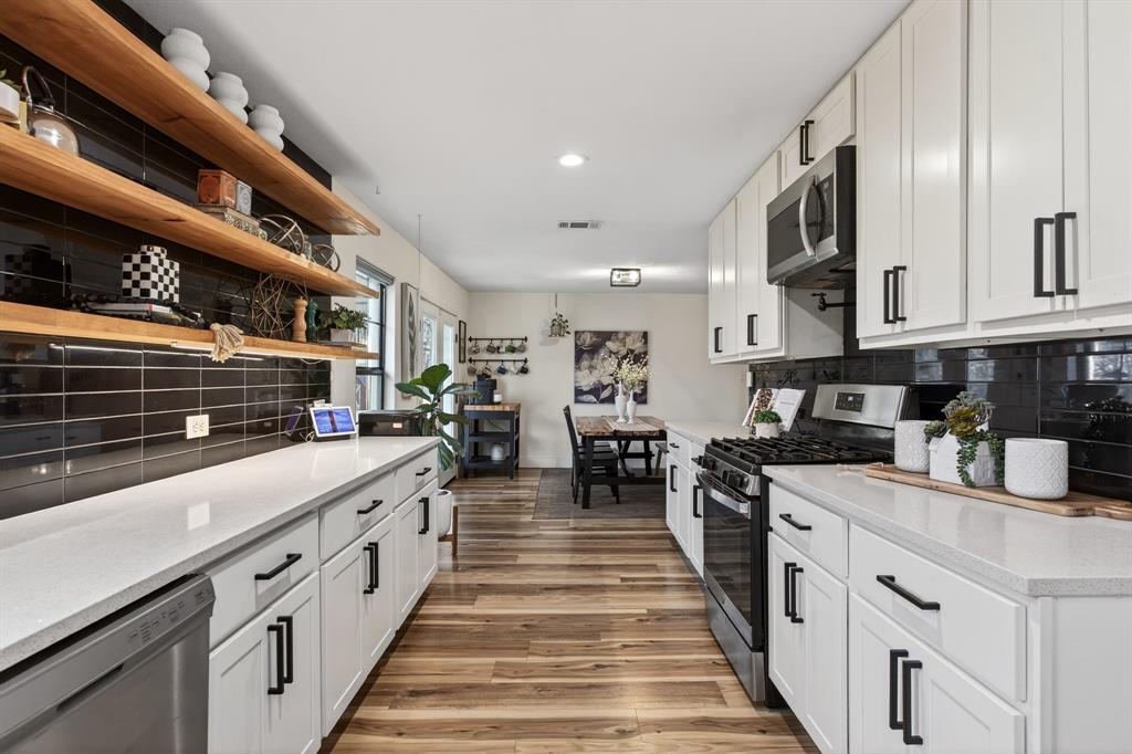 316 Old Justin Road Argyle, TX 76226 - Photo 13 of 40 Show-stopping kitchen with farmhouse sink sits beneath a window overlooking backyard panoramic views & features custom wood shelves, quartz, subway tile backsplash, gorgeous cabinetry, pot filler, 2 large pantries & mudroom.