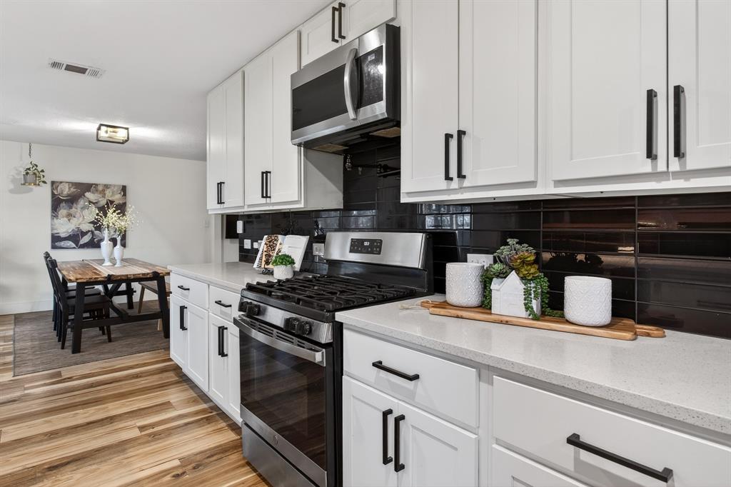 316 Old Justin Road Argyle, TX 76226 - Photo 10 of 40 Show-stopping kitchen with farmhouse sink sits beneath a window overlooking backyard panoramic views & features custom wood shelves, quartz, subway tile backsplash, gorgeous cabinetry, pot filler, 2 large pantries & mudroom.