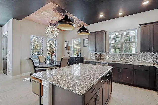 a kitchen with stainless steel appliances granite countertop a sink a stove and chairs