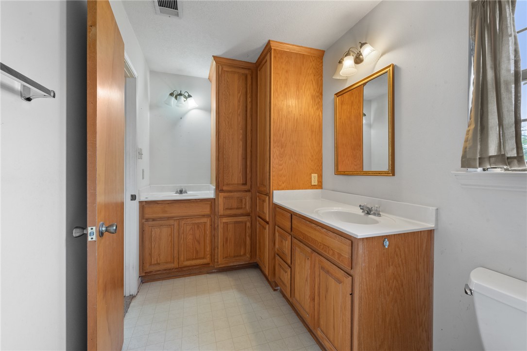 9393 Locke Road Bryan, TX 77808 - Photo 25 of 39 a bathroom with a sink a toilet and a mirror