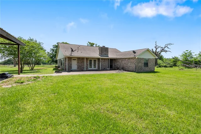 a view of a house with a big yard and large trees