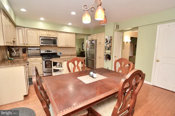 a kitchen with stainless steel appliances granite countertop a stove a refrigerator a kitchen island a sink with a dining table and chairs