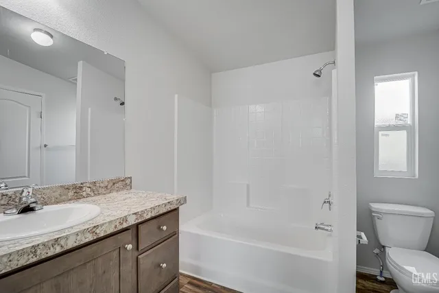 a bathroom with a granite countertop sink a toilet and shower
