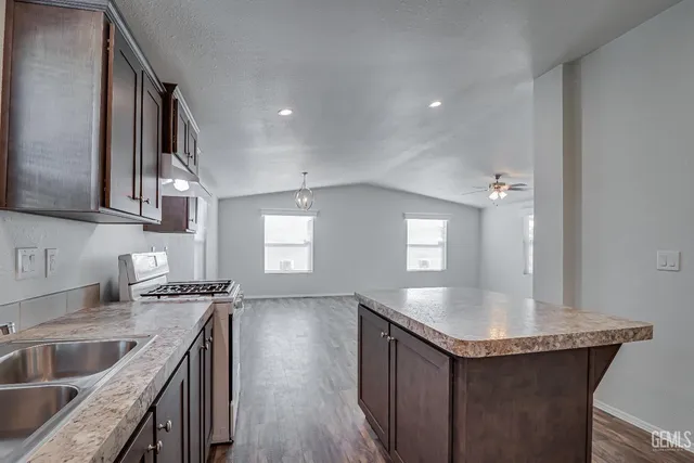 a kitchen with stainless steel appliances granite countertop a sink a stove and a wooden floors