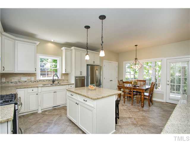8909 Breeland Way Raleigh, NC 27613 - Photo 7 of 25 a kitchen with a dining table chairs sink and wooden floor