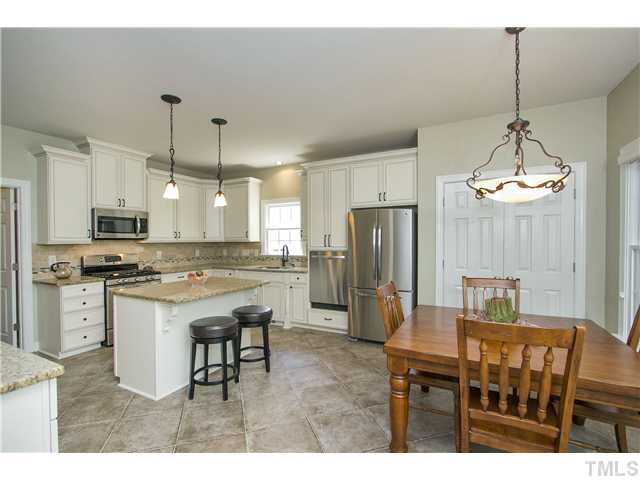 8909 Breeland Way Raleigh, NC 27613 - Photo 8 of 25 a kitchen with stainless steel appliances kitchen island granite countertop a table chairs and a refrigerator