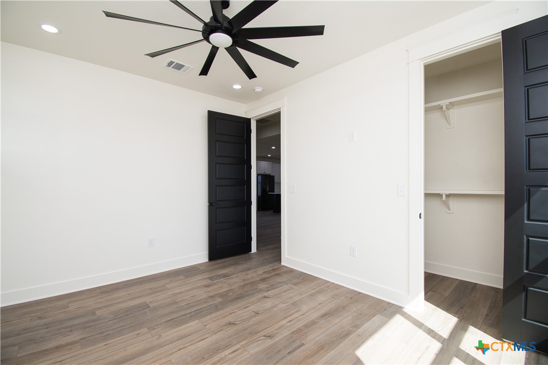 4245 Stringtown Road Temple, TX 76501 - Photo 23 of 25 an empty room with wooden floor and a ceiling fan