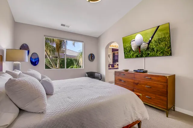 a bedroom with a bed and a lamp on dresser