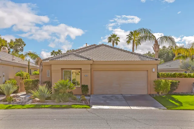 a front view of a house with a yard and potted plants
