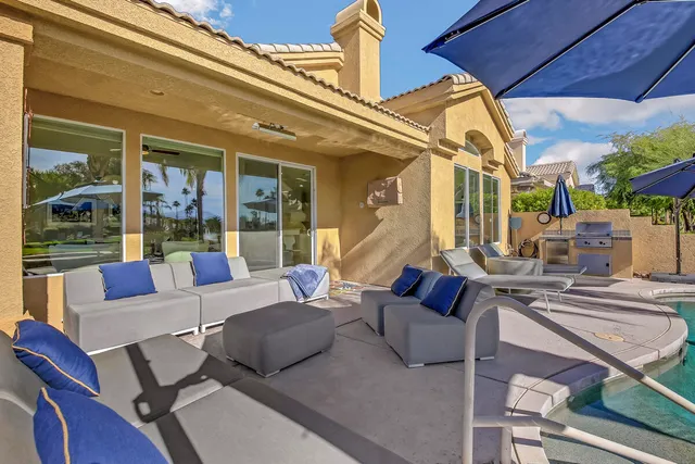 a patio with a table and chairs under an umbrella with a fire pit