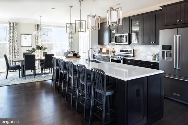 a kitchen with stainless steel appliances a table chairs microwave and view living room