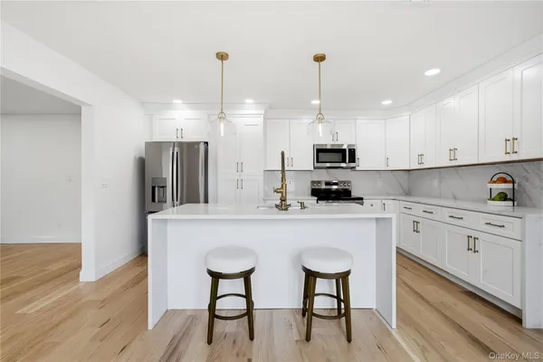 a kitchen with stainless steel appliances granite countertop a stove a sink a refrigerator and white cabinets with wooden floor