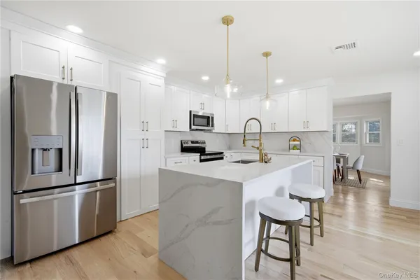 a kitchen with kitchen island a refrigerator a stove a sink and white cabinets