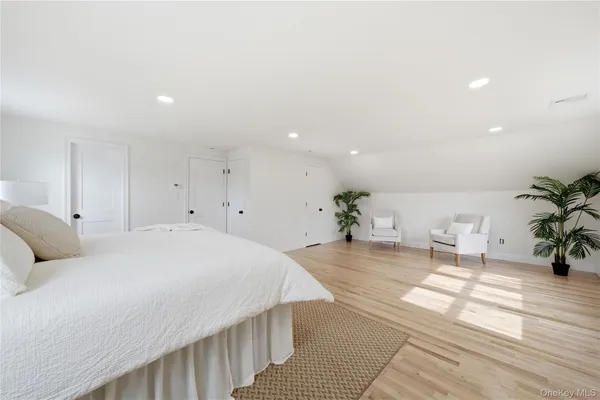 a spacious bedroom with a bed and a potted plant on table