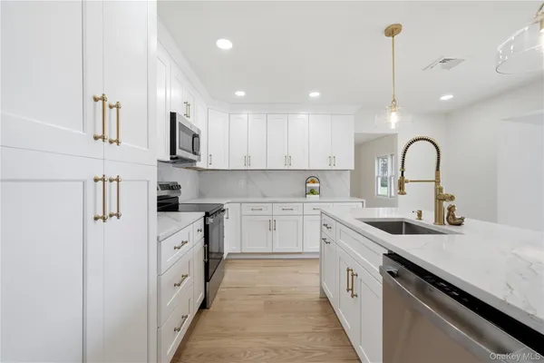 a kitchen with white cabinets appliances and a sink