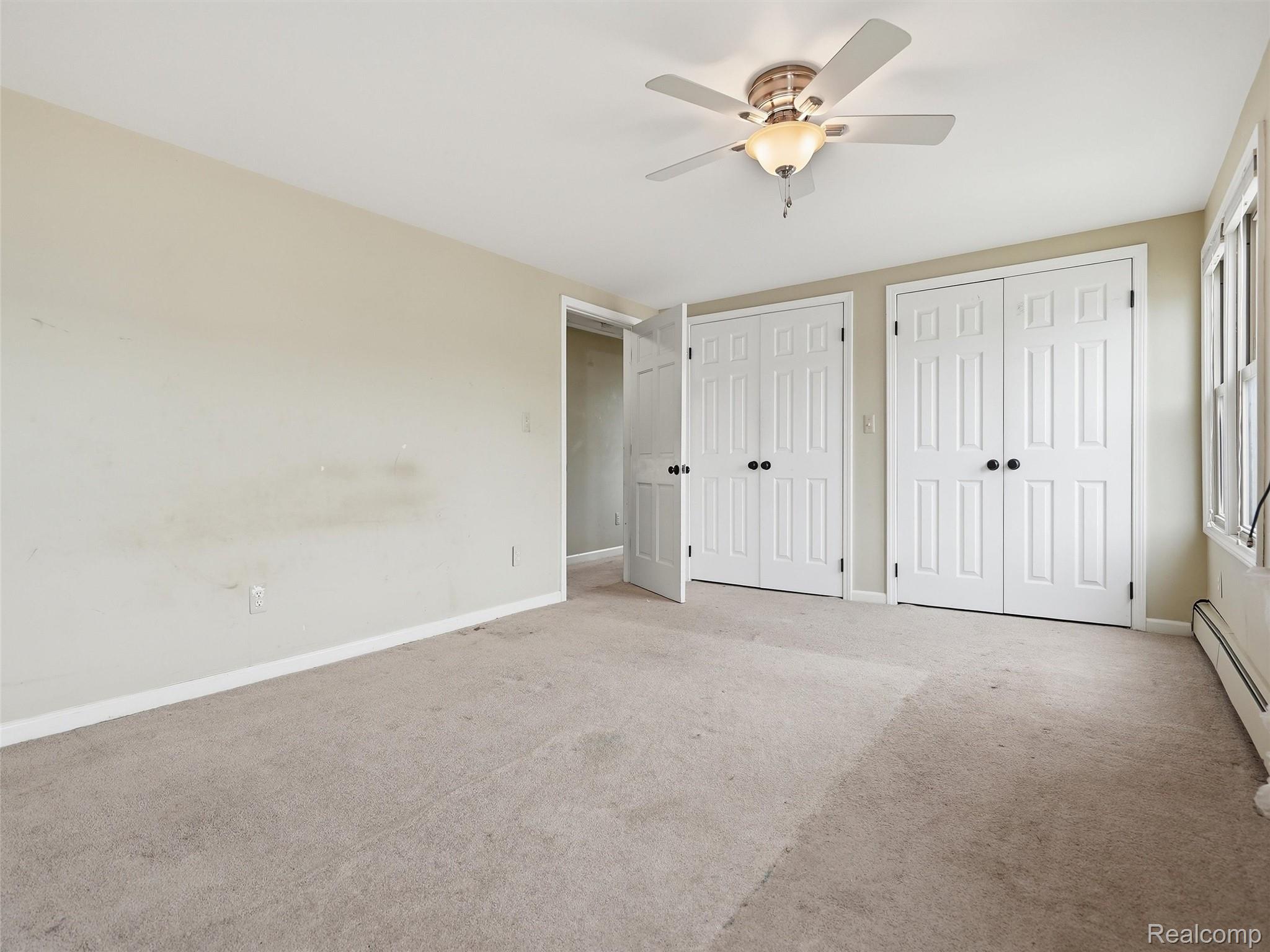 117 Kenyon Road Algonac, MI 48001 - Photo 27 of 47 Room featuring two sets of paneled bi-fold closet doors, a ceiling fan with integrated lighting, a window providing natural light, and carpet flooring