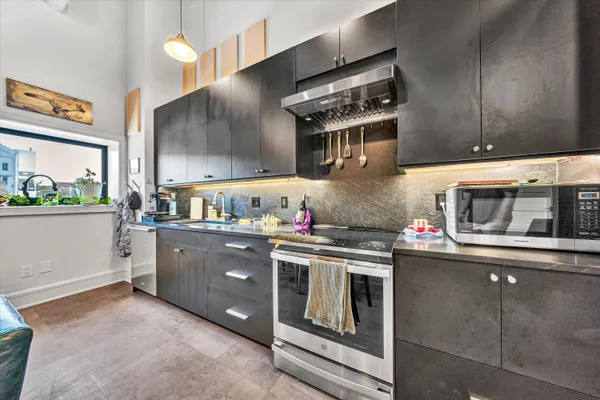 a kitchen that has a lot of white cabinets and stainless steel appliances