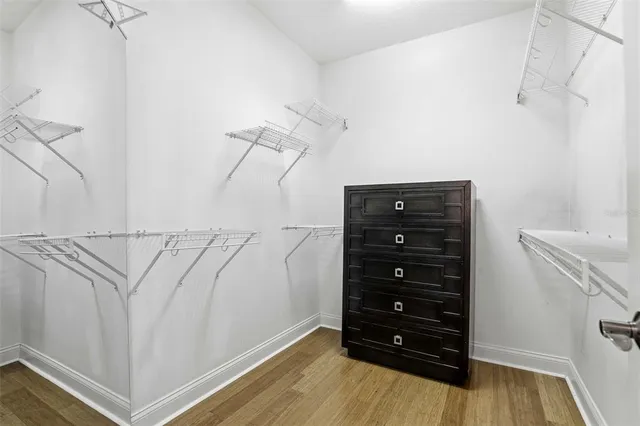 an empty room with wooden floor ceiling fan and window