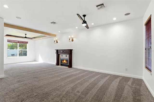 a view of an empty room with wooden floor fireplace and a window