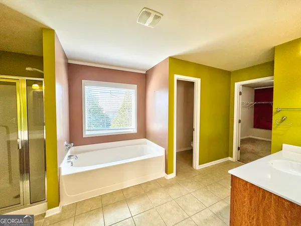 a spacious bathroom with a tub sink and mirror