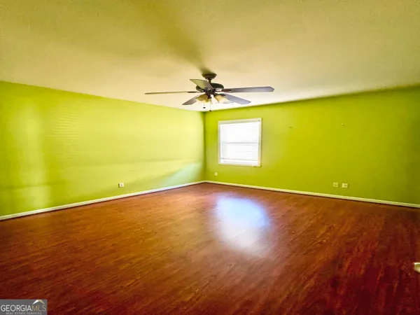 a view of a room with wooden floor and a ceiling fan