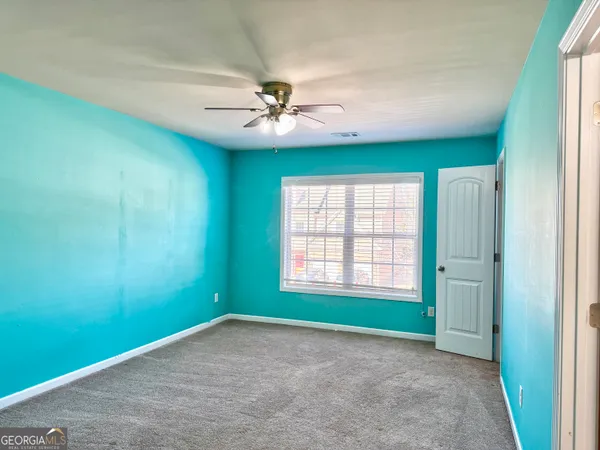 an empty room with windows and ceiling fan