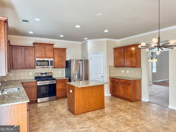 a kitchen with stainless steel appliances granite countertop wooden cabinets a stove a sink and a refrigerator